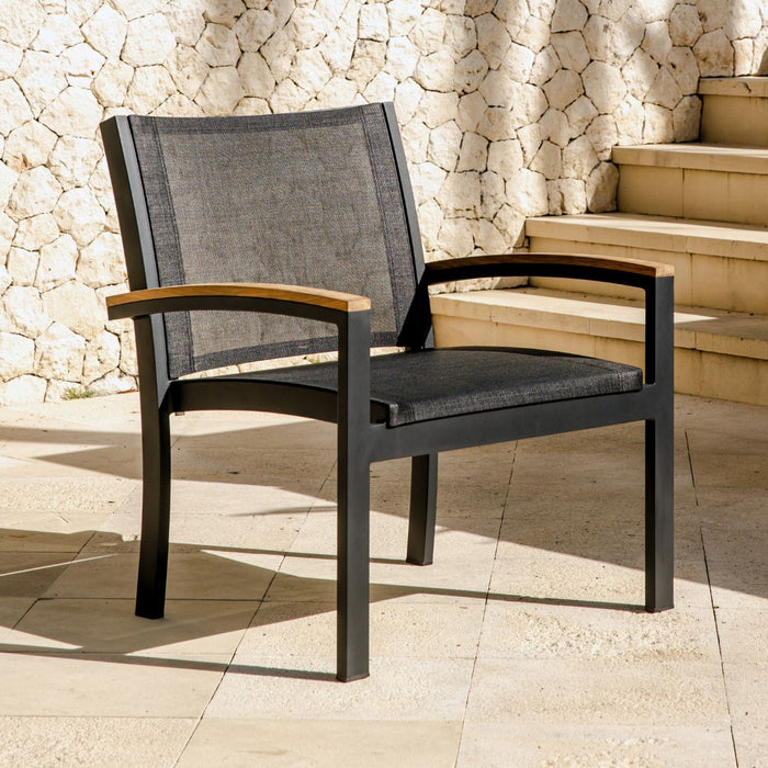 Up close shot of the Three Birds Casual Tribeca Lounge Chair with a stone wall and staircase in the background